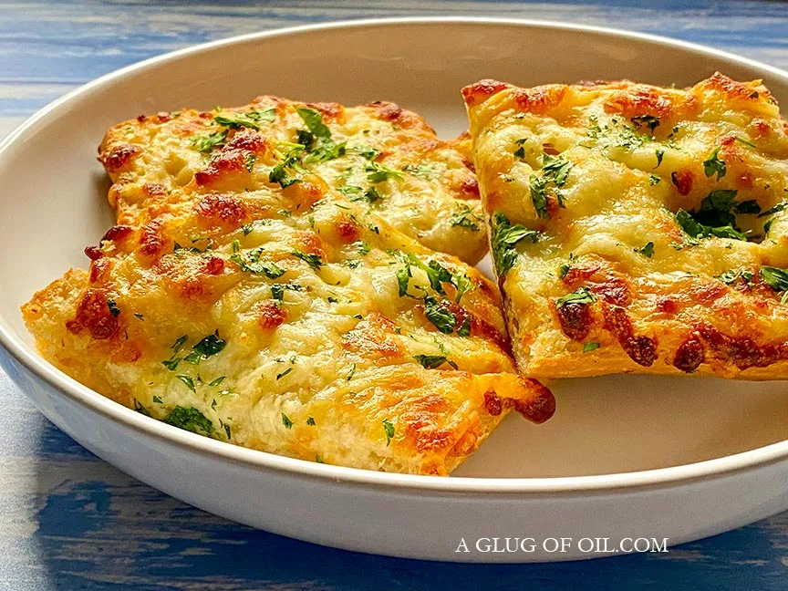 Slices of cheesy garlic bread in a bowl.