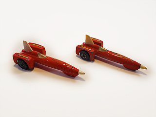 A couple of red hot wheels cars with worn flame decals on their extremely long hoods, and a white tailfin.