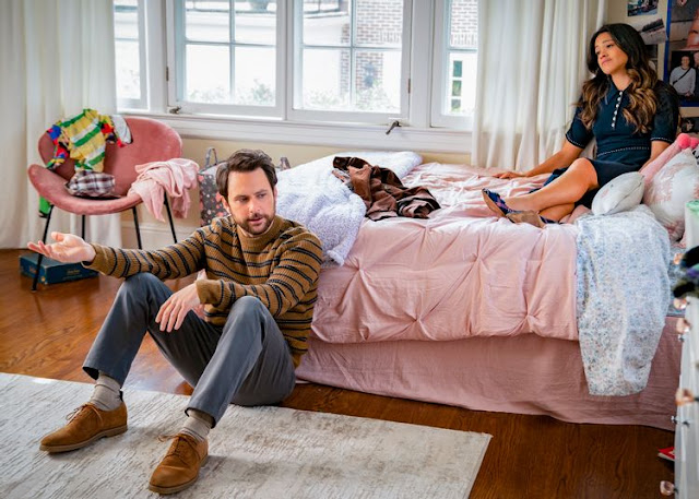 A woman sits on bed while a man sits at foot of the bed