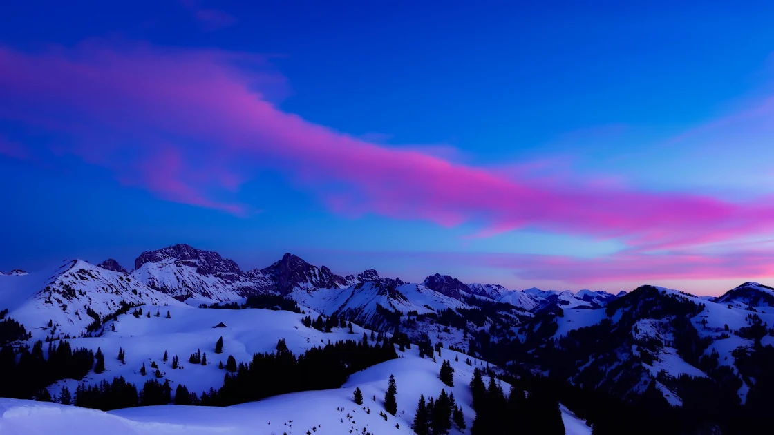 Vibrant pink clouds stretching over snow-capped mountains at sunrise, in a breathtaking 4K landscape wallpaper.