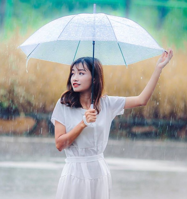 Thiếu nữ áo đầm trắng che dù dưới mưa