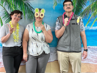 Kimball Court staff standing with props in front of beach photo backdrop