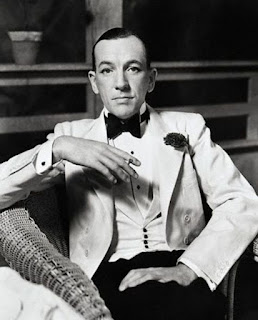 Noel Coward in white tuxedo holding cigarette