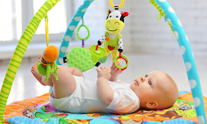 A cute 6-month-old baby playing with a colourful toy arch that can prevent future eye problems.