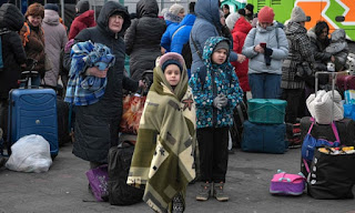 People fleeing the war in Ukraine stand with their luggage as they wait to board buses near the Polish city of Przemyśl. Photograph: Louisa Gouliamaki/AFP/Getty Images