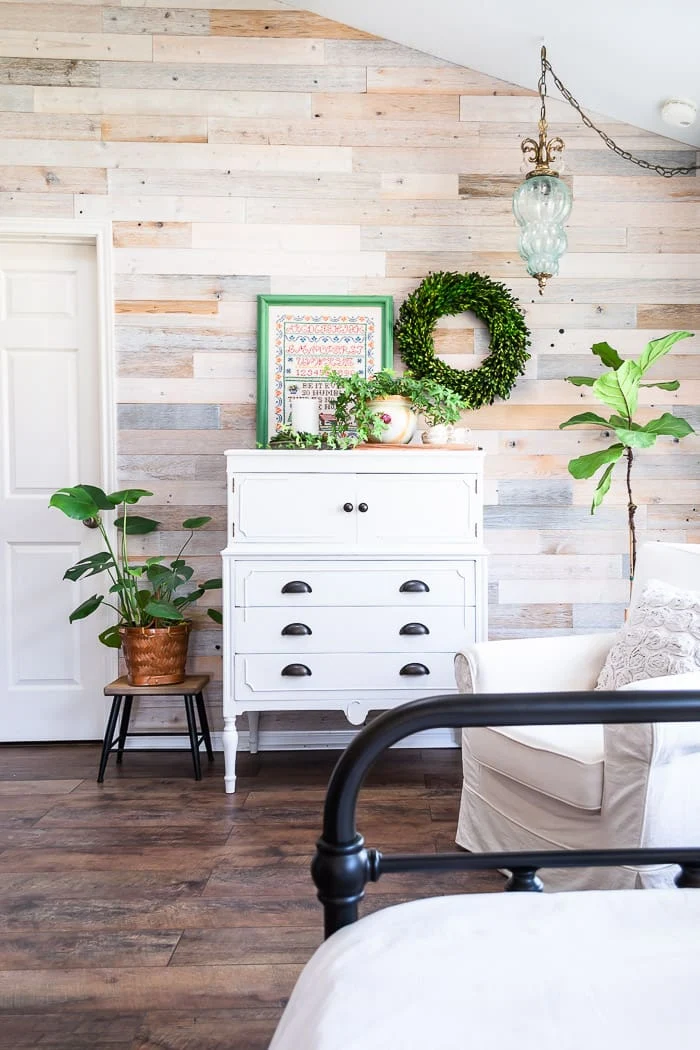 white cottage dresser against reclaimed wood wall, plants, vintage blue light