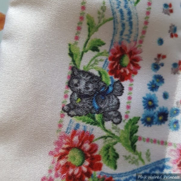 close up of grey kitten printed on floral background of satin pouch