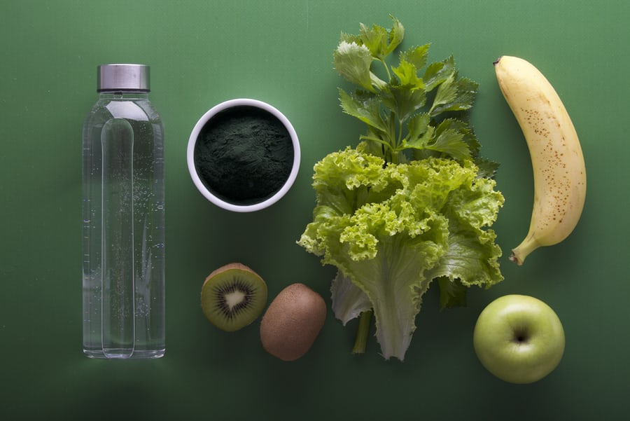 A bottled water, leafy vegetable, banana, apple, guava and other fruits used for losing weight effectively arranged beautifully on a tray