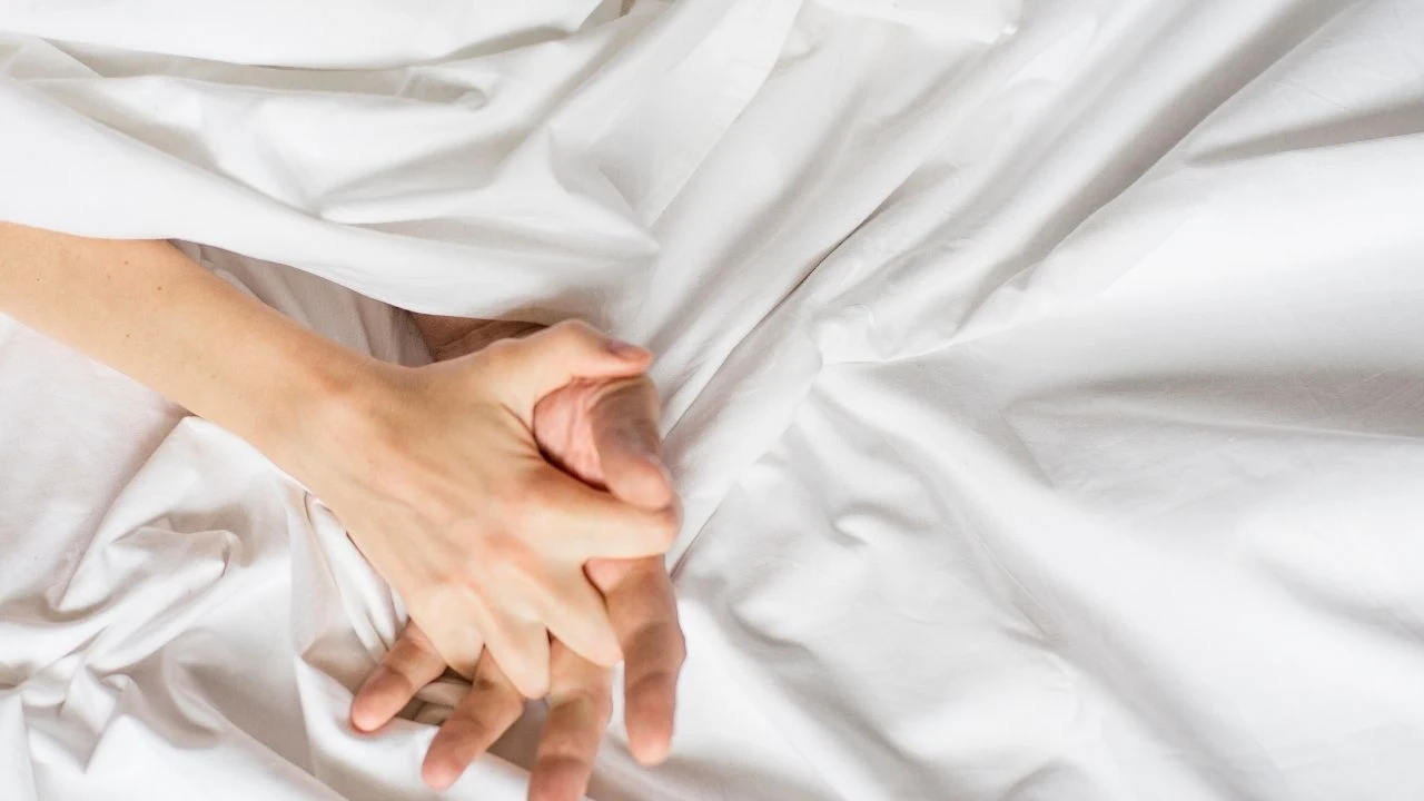 Hands of a couple in bed, man and woman having sex.