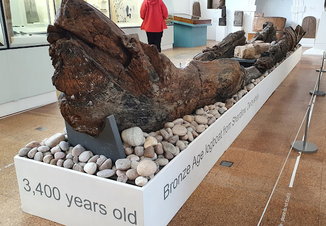 Full size remains of Wooden Bronze Age longboat resting on a base of pebbles and stone