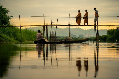 Monks crossing bamboo bridge in Thailand