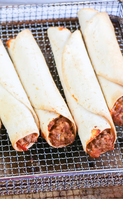 taquitos in an air fryer basket.