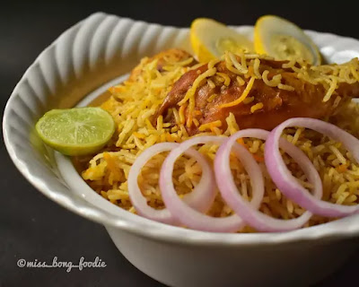 Biryani presented along with onion slices and lemon