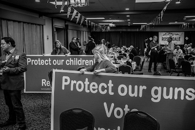 black and white photo of Montana Republican Convention with large signs "Protect Our Children" and "Protect our Guns)