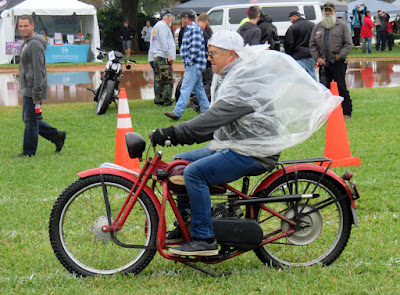 Man rides motorcycle in rain pancho.