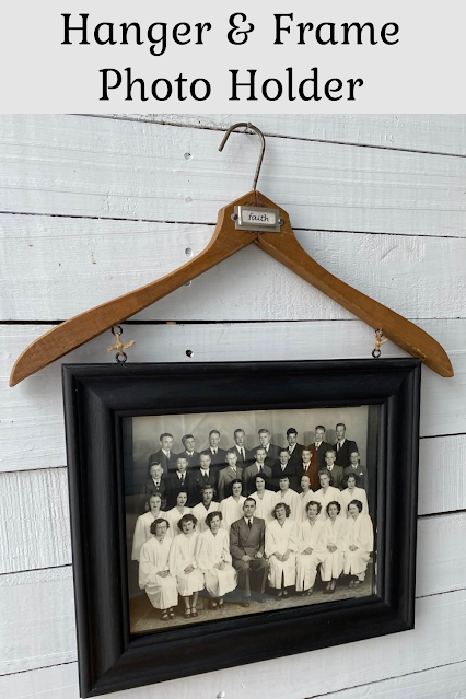Photo of a vintage confirmation day picture framed in a black frame hanging from a vintage wooden clothes hanger.