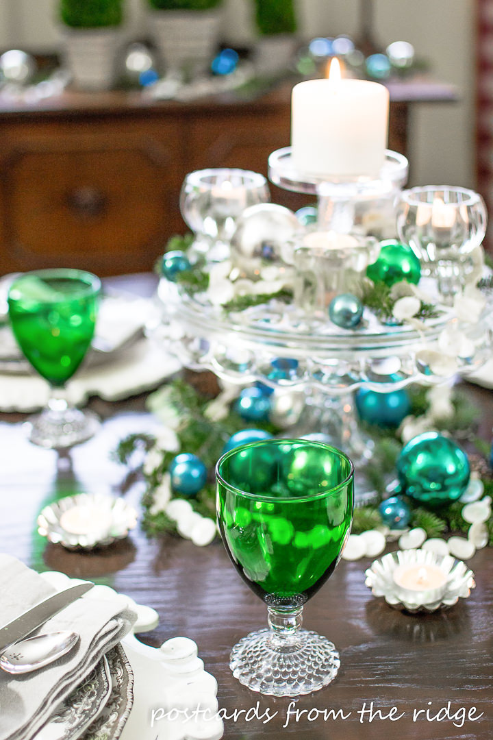 vintage green goblets with blue and green ornaments and candles on a Christmas table