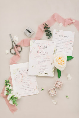 wedding details with invitations, pink ribbon and greenery