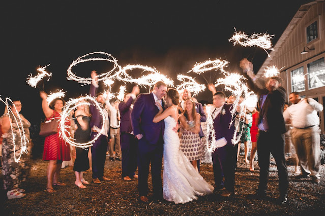 bride and groom kissing in front of friends holding sparklers