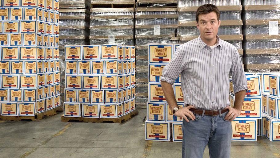 Jason Bateman standing in front of scores of cases of Reynold's Extract