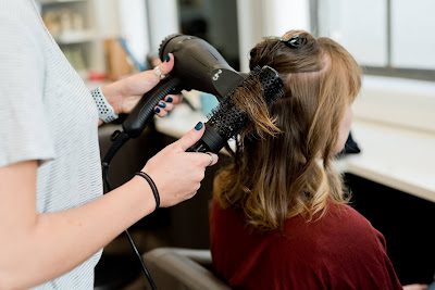 Peluquera secándole el pelo a una clienta