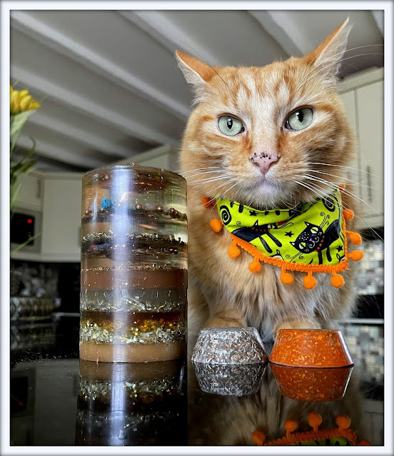 Ginger cat sitting next to orgonite tower and orgonite cakes