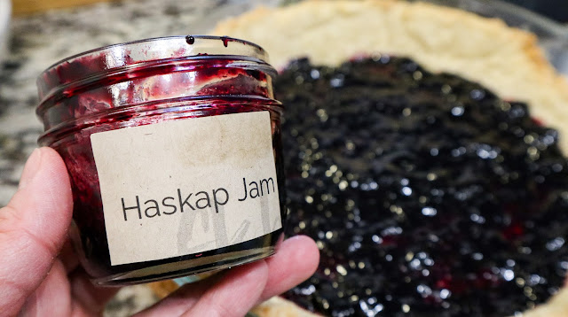 Homemade haskap Jam in a glass jar with the pie under