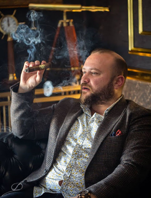 Bear sitting wearing grey suit blowing smoke rings.