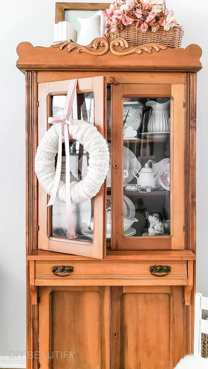 neutral winter wreath hung on pine cabinet