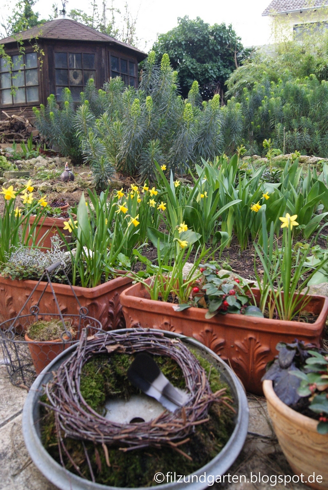 Gartendeko mit Mooskranz im Zinkdeckel und Narzissen