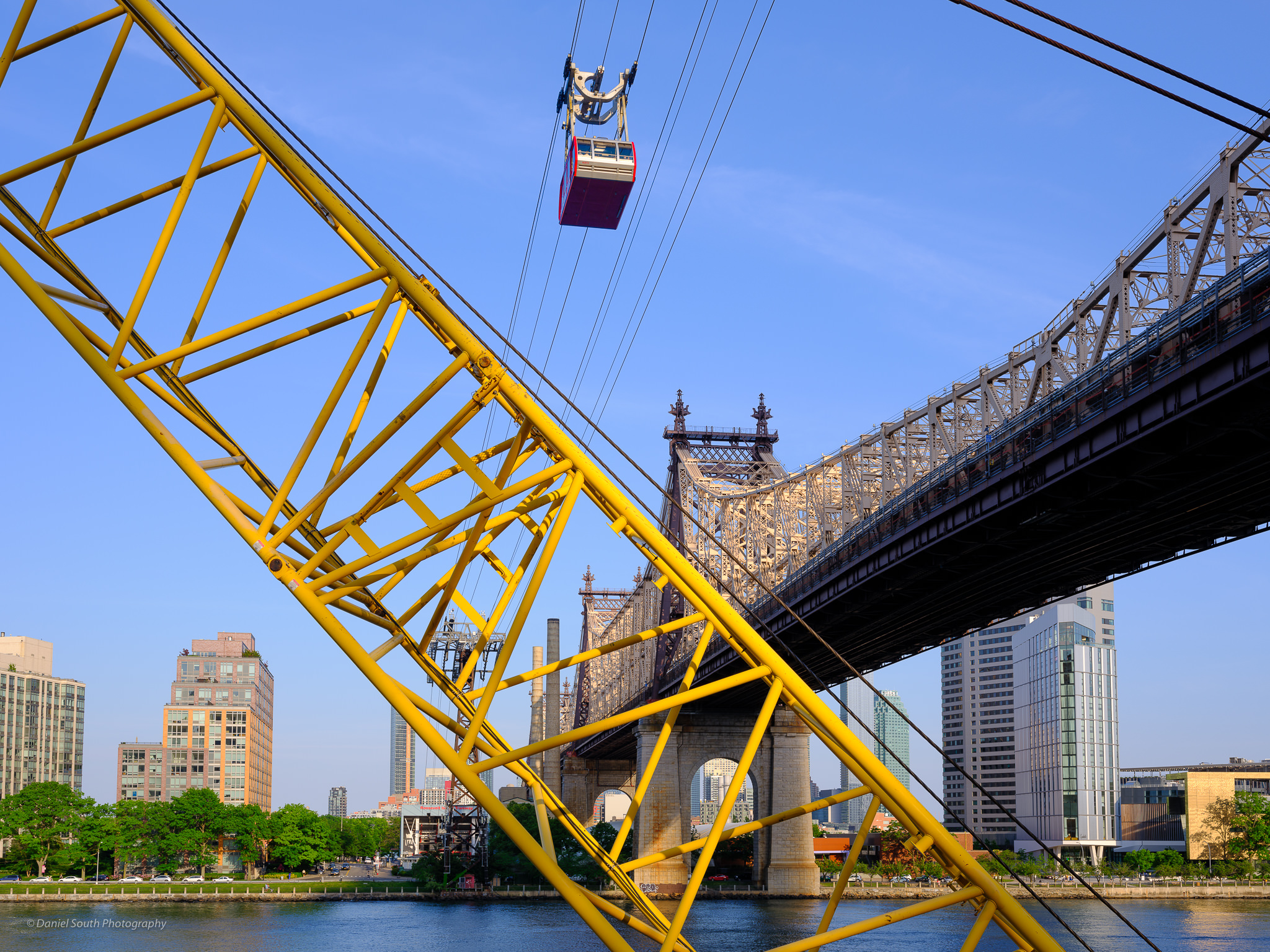 a photo of a yellow crane and a cable car near the queensboro bridge in new york