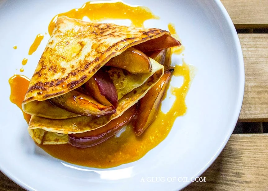 Pancakes with caramelised nectarines on a white plate.