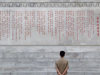 Bir Kuzey Kore yurttaşı kuledeki Kim İl-sung'e atfen yazılmış şiiri okuyor, 2012