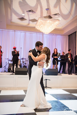 bride and groom kissing on black and white checkered dancefloor