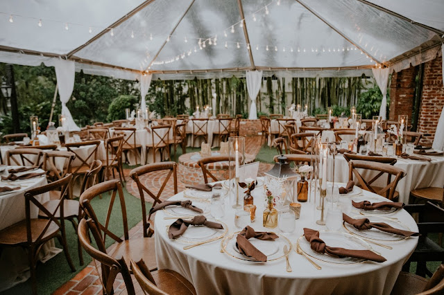 reception with round tables with clear chargers and brown napkins  under clear tent