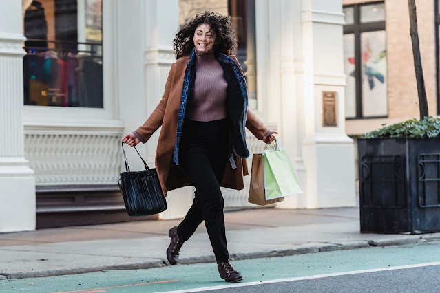 A happy female shopper crossing the street.