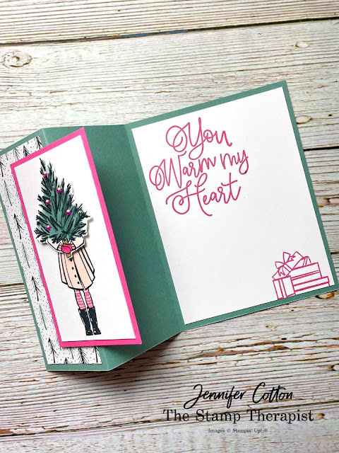 Christmas card using Stampin' Up! Delivering Cheer stamp set.  Z fold (fold the front 1/2 back to the left and then attach an image to the flap).  Girl in coat holding a Christmas tree.  When you open it says You Warm My Heart (Encircled in Warmth stamp set) in Polished PInk.  Card base is Soft Sucuclent.  Girl is colored with Stamin' Blends: petal pink, polished pink, evening evergreen, soft succulent.  Jennifer Cotton.  More details on video on blog.