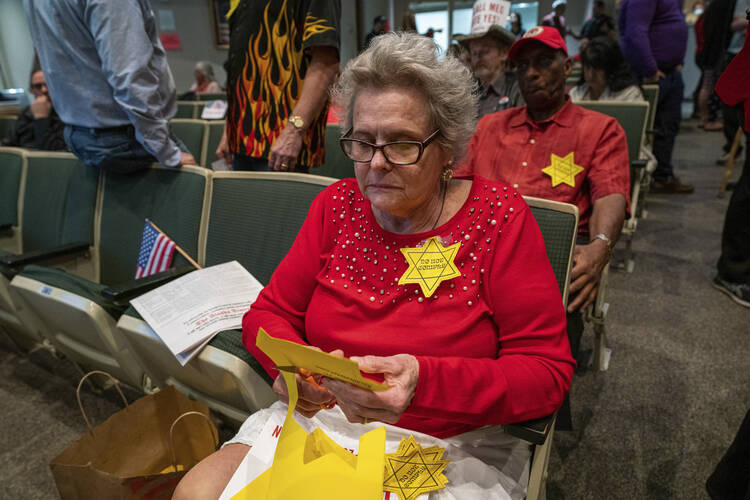 Christine Hill cuts out yellow Stars of David before an Anchorage Assembly meeting about a proposed mask mandate on Sept. 29, 2021, in Anchorage, Alaska. (Loren Holmes/Anchorage Daily News via AP)