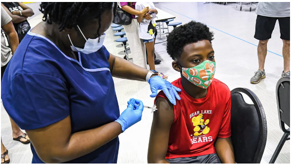 Una enfermera le da a un niño una dosis de la vacuna Pfizer en una clínica de vacunación COVID-19 en Lyman High School en Longwood, FL, el día antes de que comiencen las clases para el año escolar 2021–22. Imágenes SOPA / Getty Images