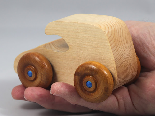 Handmade wooden toy car. The body is finished with clear shellac, and the wheels are finished with amber shellac. The hubs are painted with metallic sapphire blue trim.
