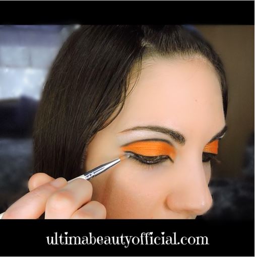 Ultima Beauty applying white eyeshadow between eyeliner wings with a small eyeshadow brush