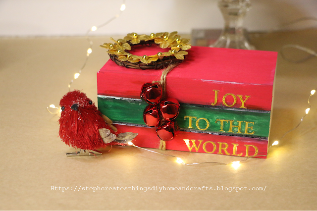 Christmas wooden book stack painted red and green. Gold letters read Joy To The World.