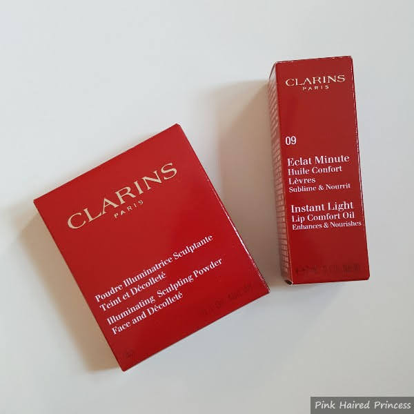 red Clarins boxes of highlighter and lip oil on white background