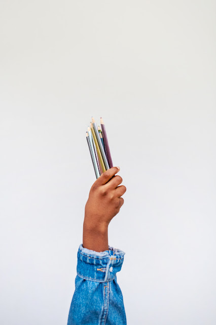 A hand holding colored pencils.