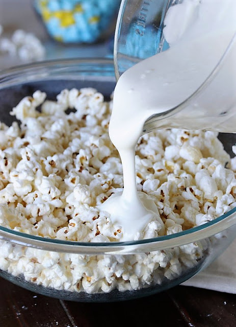 Pouring Melted White Chocolate Over Popped Popcorn Image