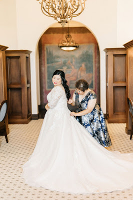 bride getting dress fixed by mother