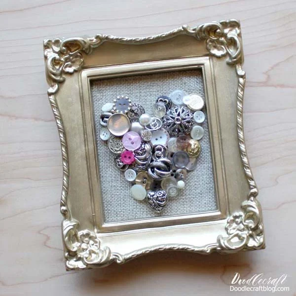 How to Make a Vintage Button Heart Frame! Learn how to make a vintage button heart in an ornate frame. Pull out those old vintage buttons in the cookie tin and turn them into a beautiful piece of decor for the home. Gather a few supplies from around the house or take a trip to the dollar store to get the necessary items for this craft.  It's a great handmade gift, perfect decor for Valentines day or year round, and can be done as a kids craft project too!