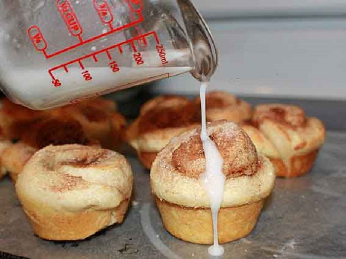 cinnamon rolls made in a muffin tin with rich icing poured on top