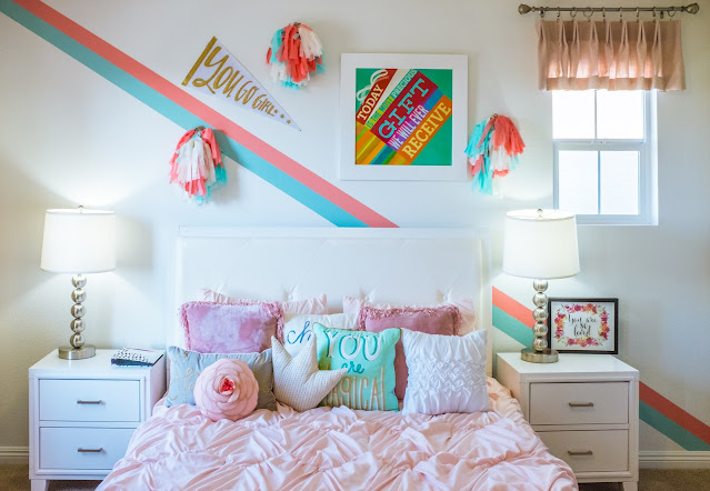 Children's room double bed made up with cushions and wall art in the background