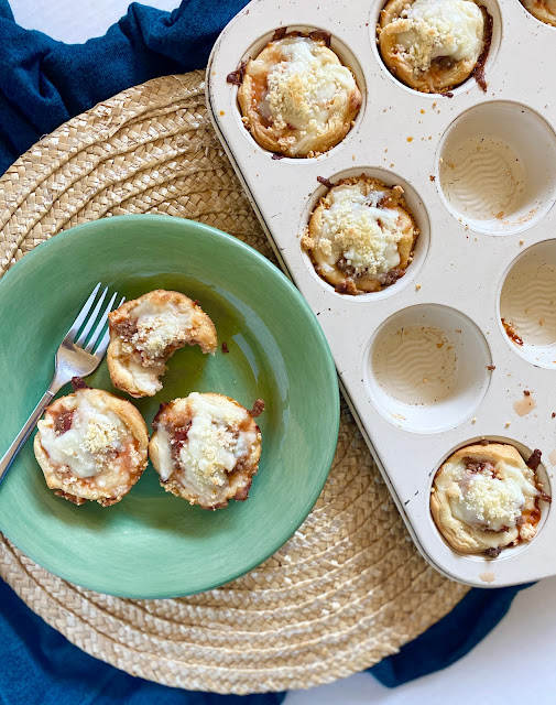 Baked Lasagna Cups on a green plate next to a muffin tin of appetizers